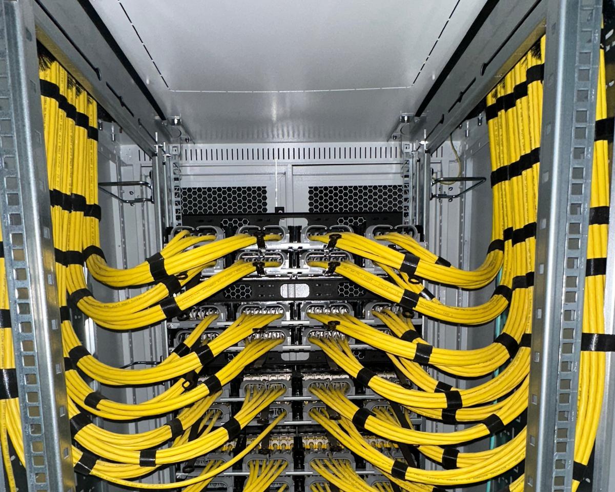 Achterkant van een patchkast: gele Cat6a-bundels in gelijke bogen naar de panelen